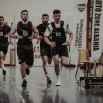 Group of men running in an indoor fitness competition, showcasing athleticism and determination.